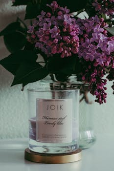 玻璃杯中，盛开的丁香花与薰衣草香味的蜡烛精致地排列在一起