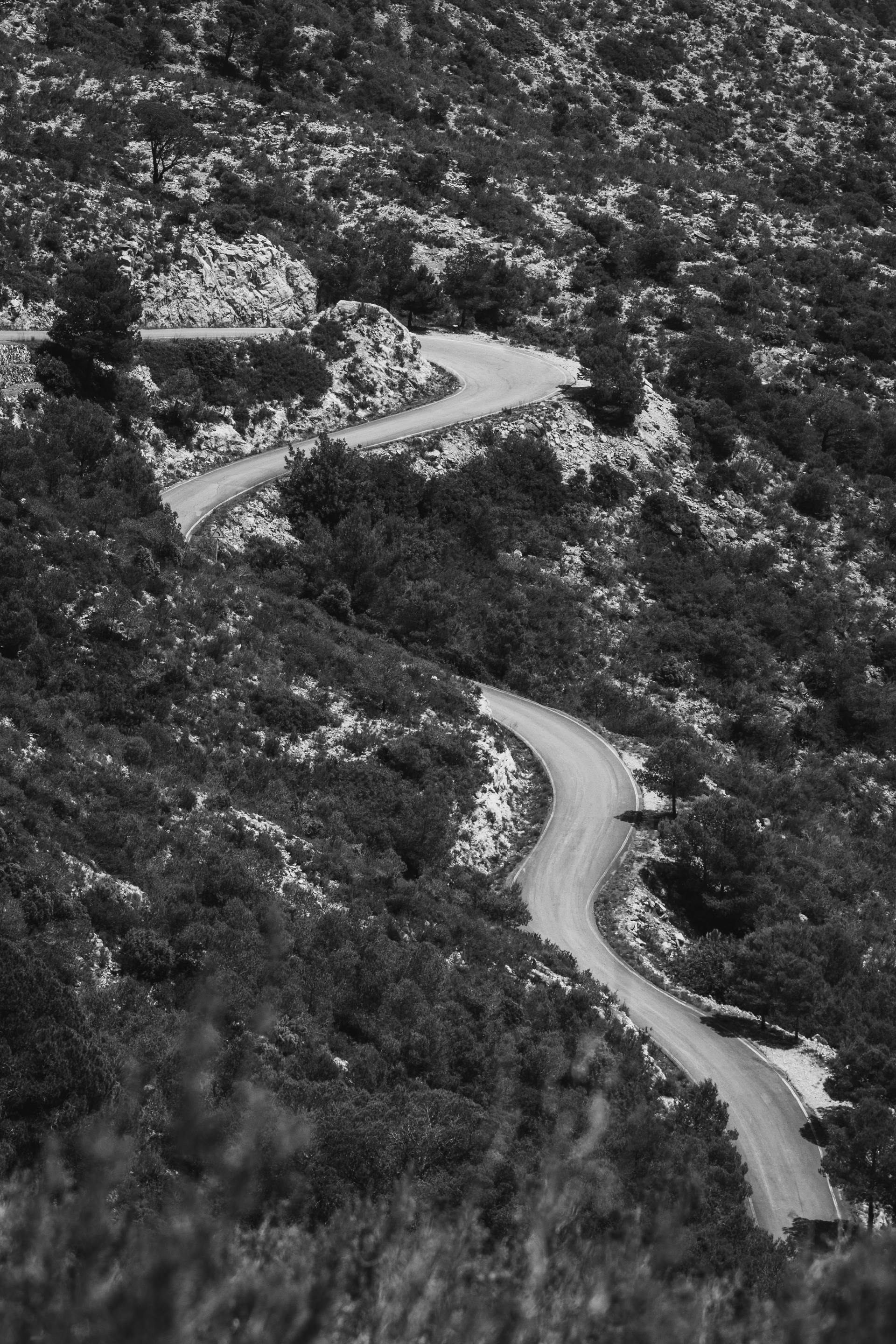 Black and white photo of a winding road through a rocky terrain, evoking calm and serenity.