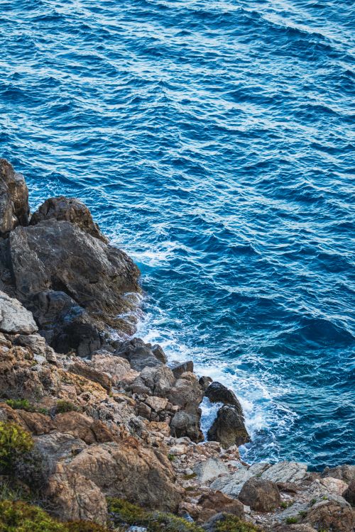 Free A picturesque rocky coastline with vibrant blue ocean waves creating a natural seascape. Stock Photo