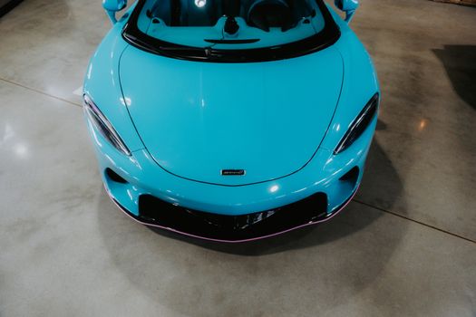 High-angle shot of a bright turquoise sports car parked indoors on concrete flooring.