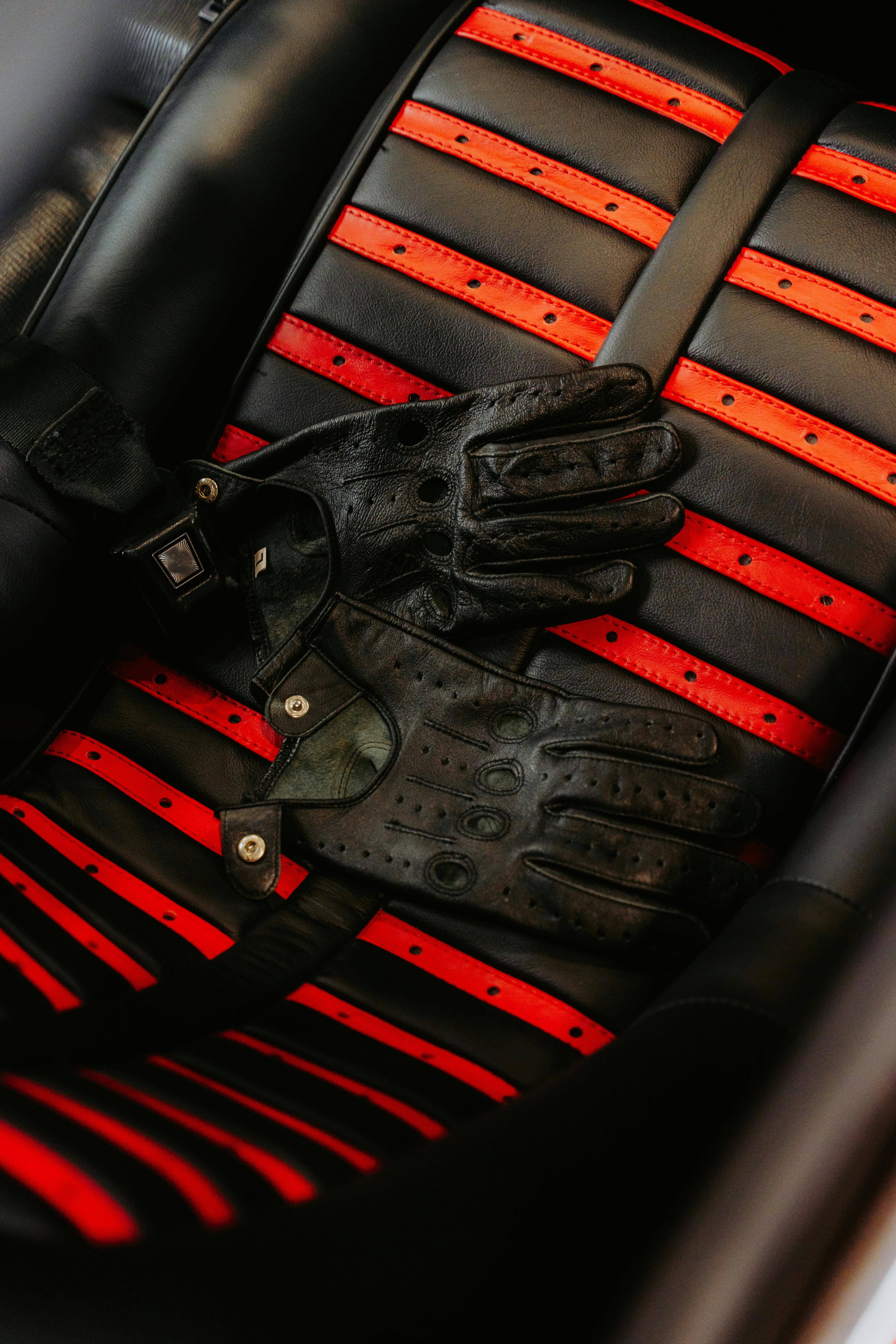 Gants de conduite cuir noir sur siège rayé rouge
