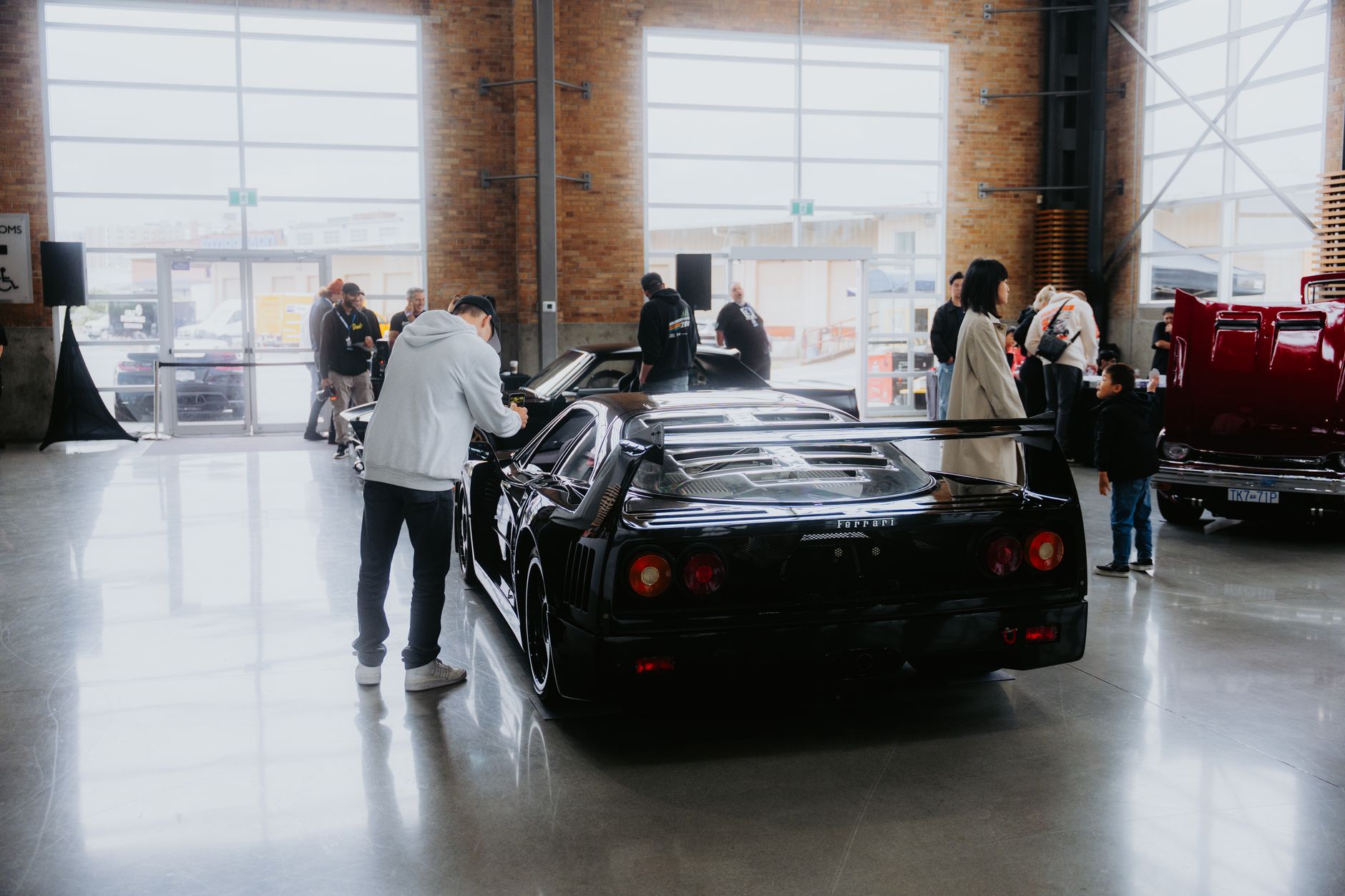 Classic Ferrari on display indoors with people viewing at a car show event.