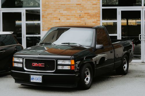 Free A sleek black GMC pickup truck parked outside a commercial building. Stock Photo