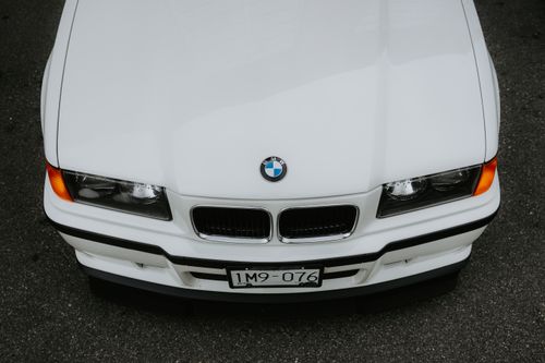 Free Top-down shot of a classic white BMW on an asphalt road, showcasing its sleek design. Stock Photo