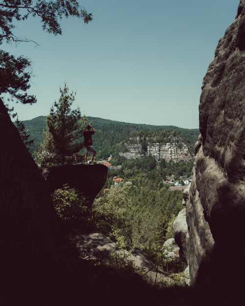 Free A hiker stands on a rocky outcrop in Naturpark Zittauer Gebirge, overlooking lush forest and cliffs. Stock Photo