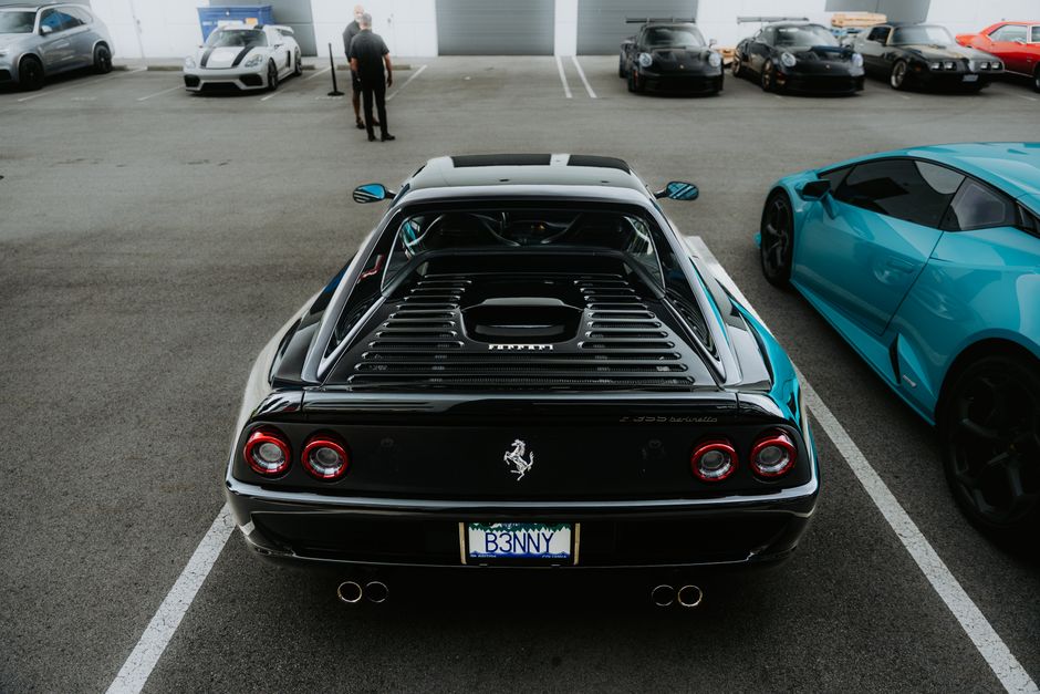 A high-end Ferrari parked among other luxury sports cars, showcasing automotive elegance in an open lot.