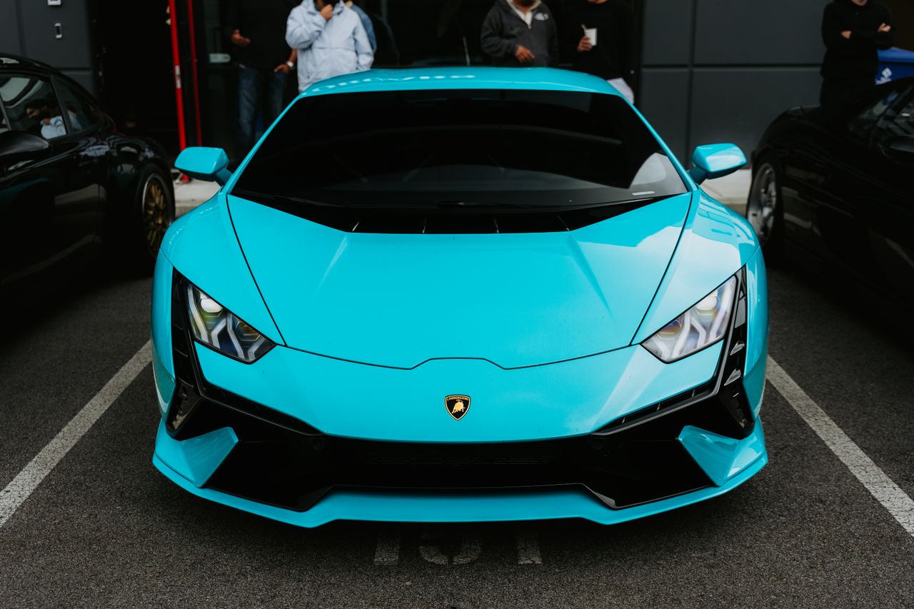 front view of a sleek blue sports car parked outdoors at an auto show