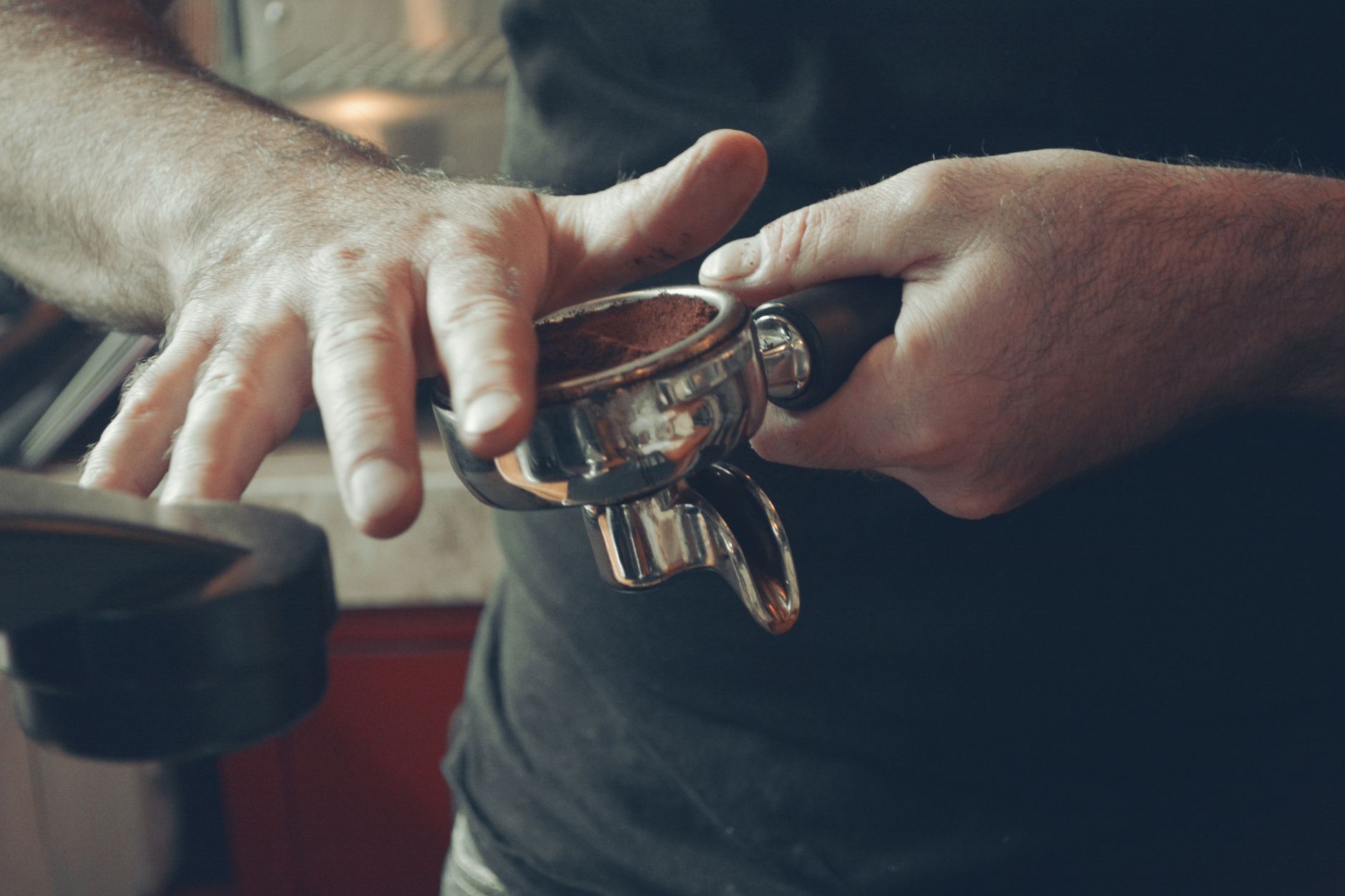 Close-up of a barista tamping coffee grounds in a portafilter in an Ecuador cafe.