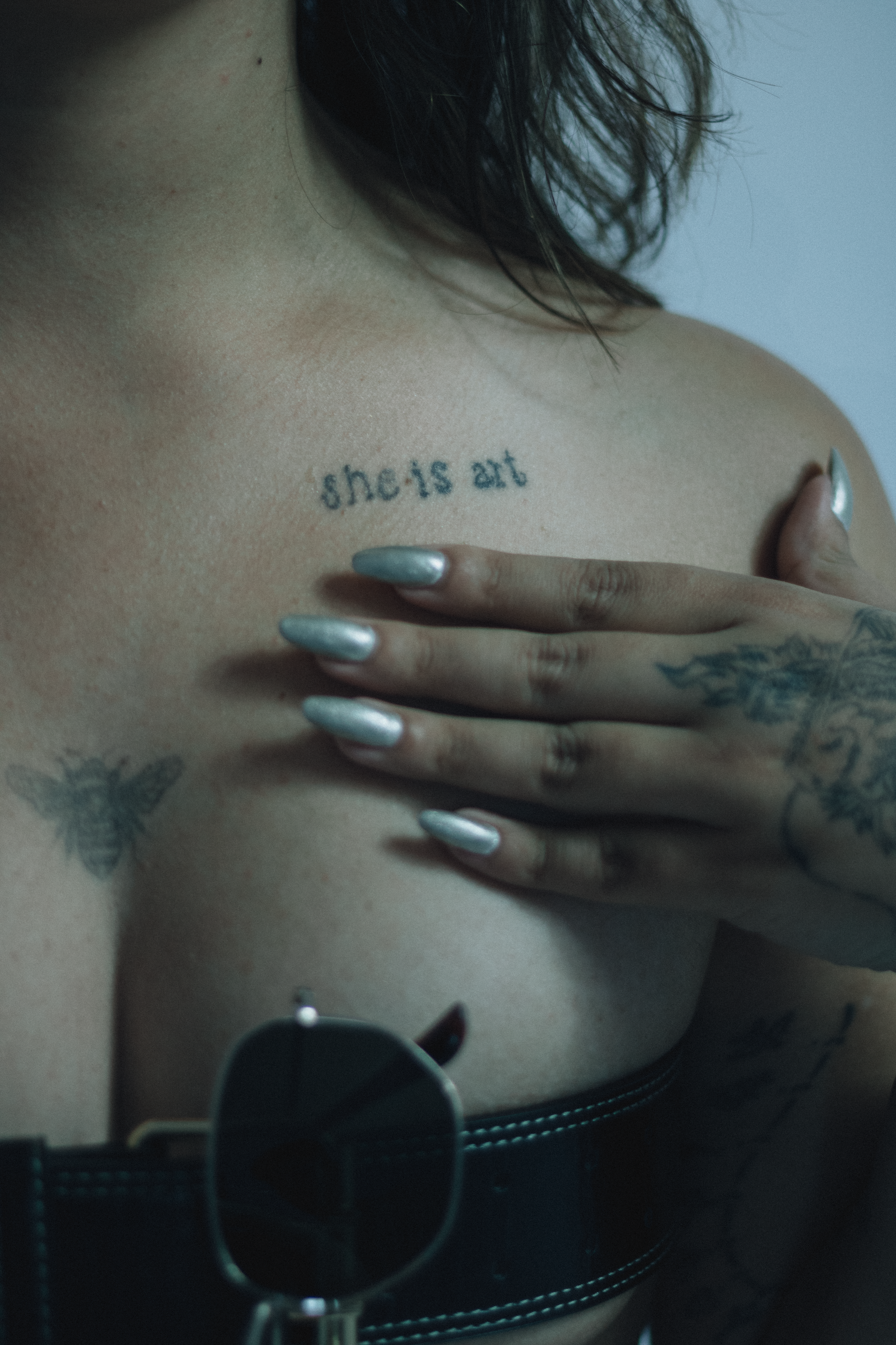 Close-up of a woman's shoulder tattoo with artistic text and designs, exuding style.