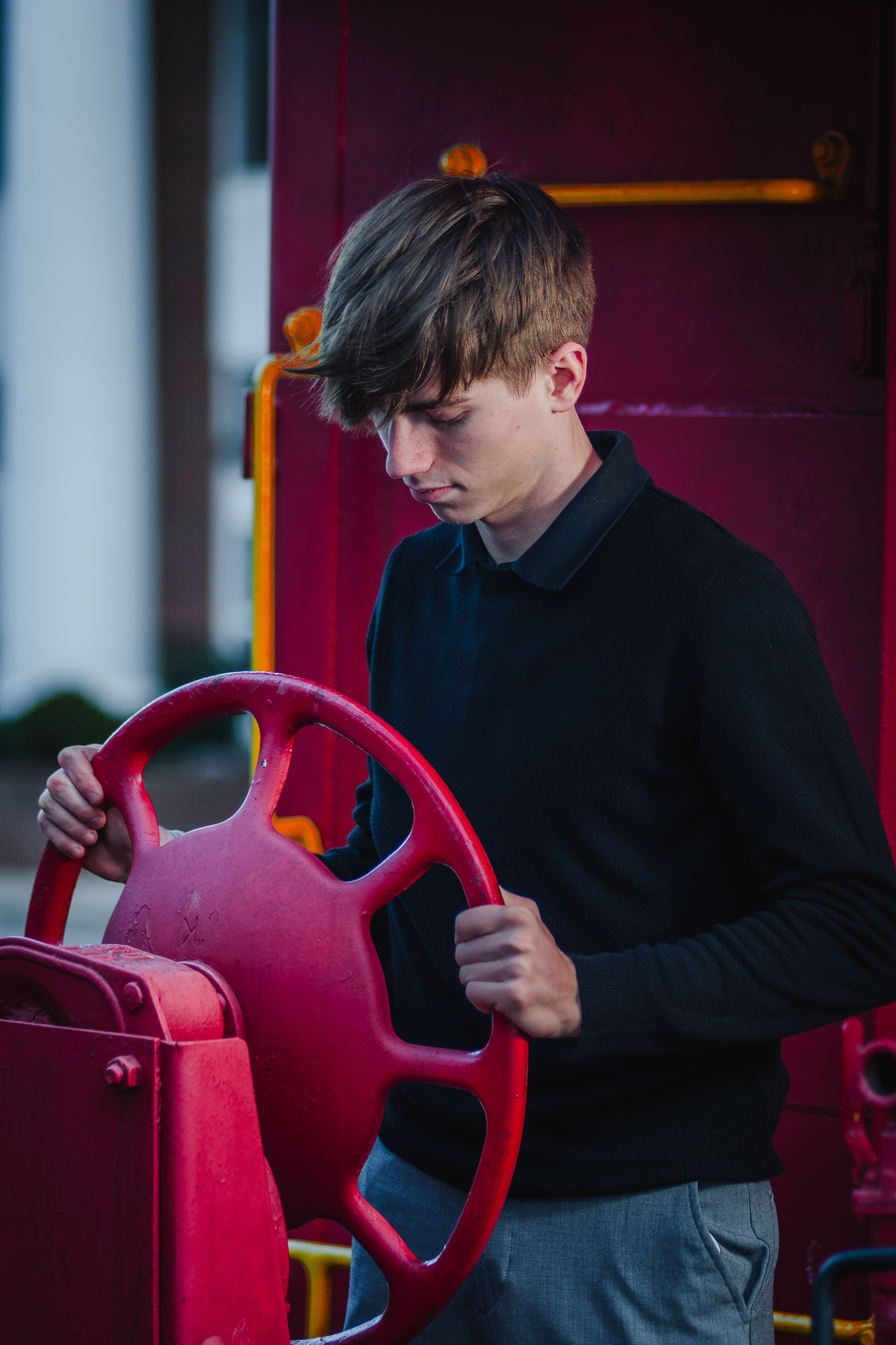 Young man operating a vibrant red steering wheel outdoors during the day.