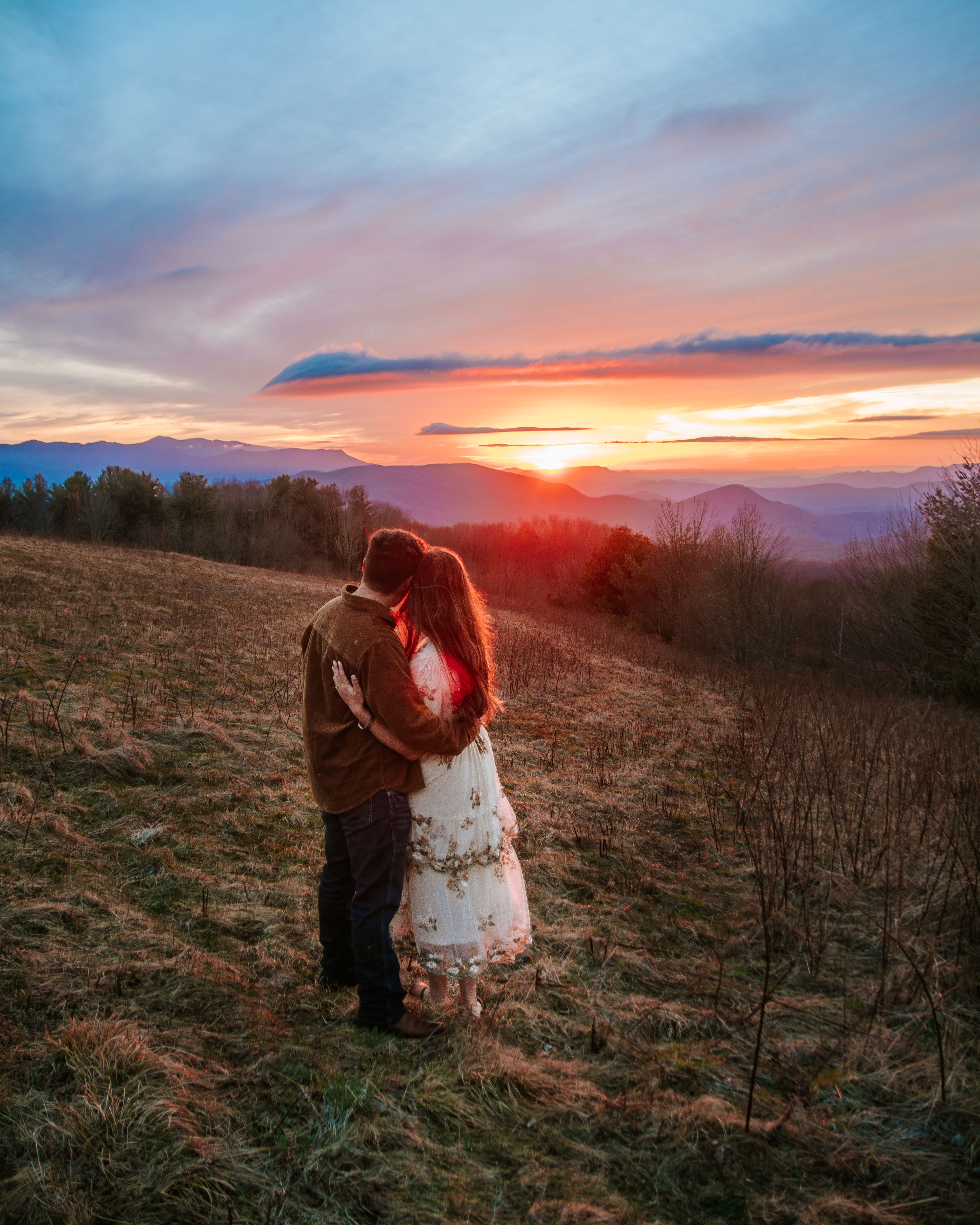 Romantic Sunset Embrace in Scenic Mountain Field · Free Stock Photo