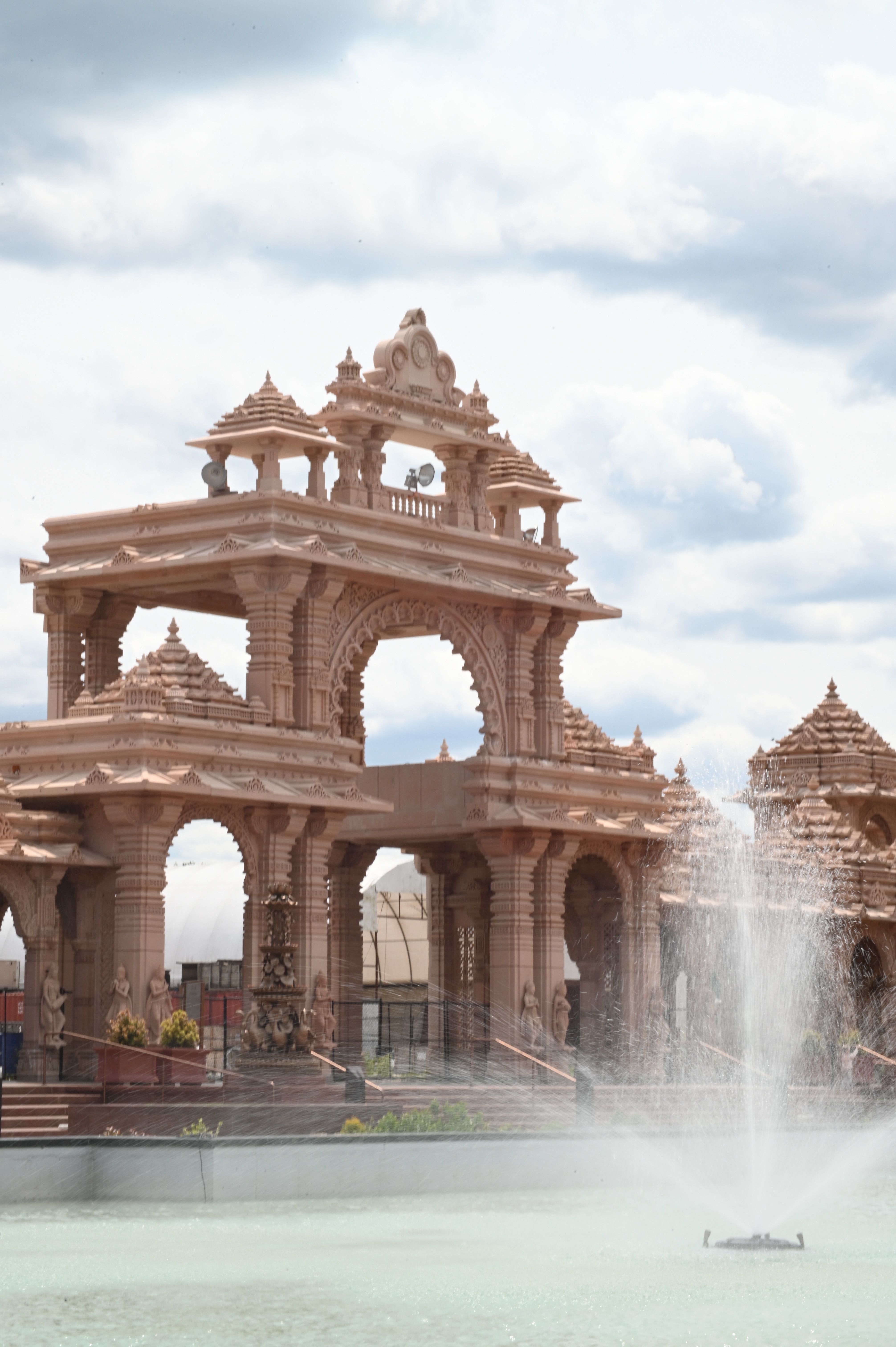 Stunning view of a historic Indian temple with a fountain, set against a partly cloudy sky.