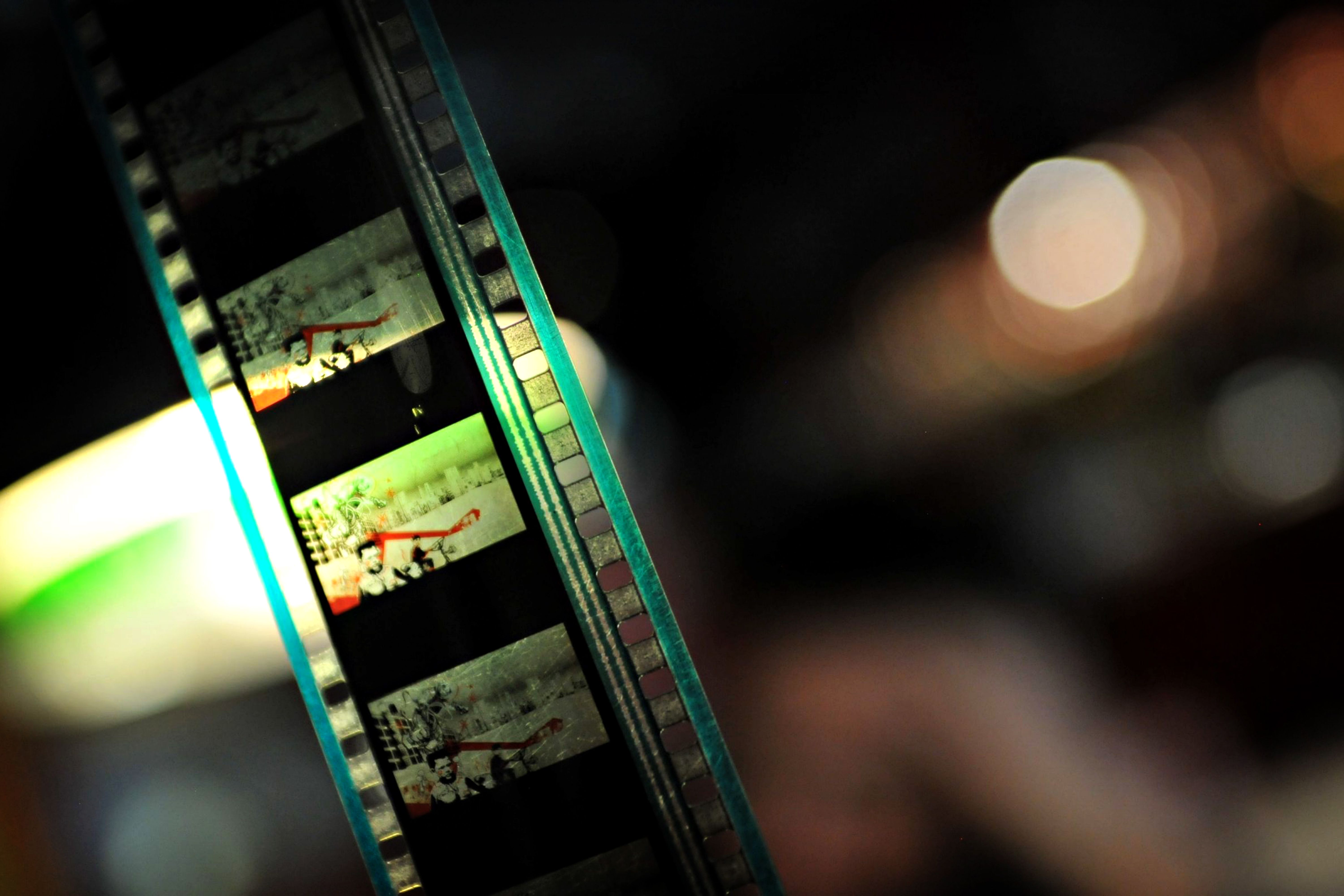 Free Detailed close-up of a film strip with colorful lights and soft bokeh in the background, creating a nostalgic feel. Stock Photo