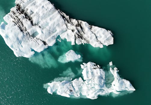 Aerial view of icebergs melting in the turquoise waters of Iceland, highlighting climate change impact.