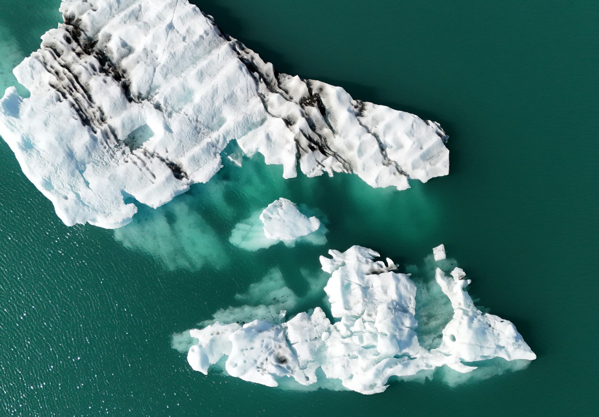 Aerial view of icebergs melting in the turquoise waters of Iceland, highlighting climate change impact.
