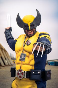 Dynamic photo of a man in a Wolverine costume posing outdoors at a cosplay event.