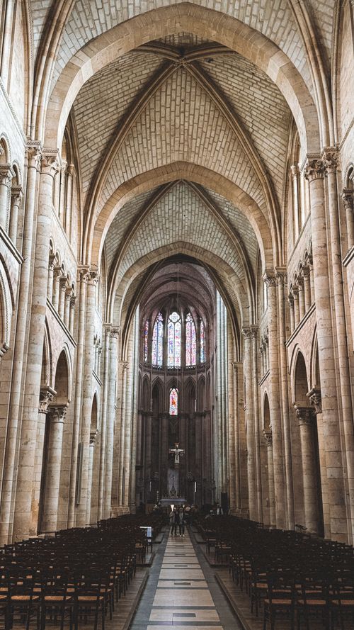 Free Stunning view of a Gothic cathedral interior featuring high vaulted ceilings and stained glass windows. Stock Photo
