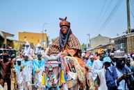 Vibrant Nigerian cultural procession with traditionally dressed horsemen in a lively street festival.