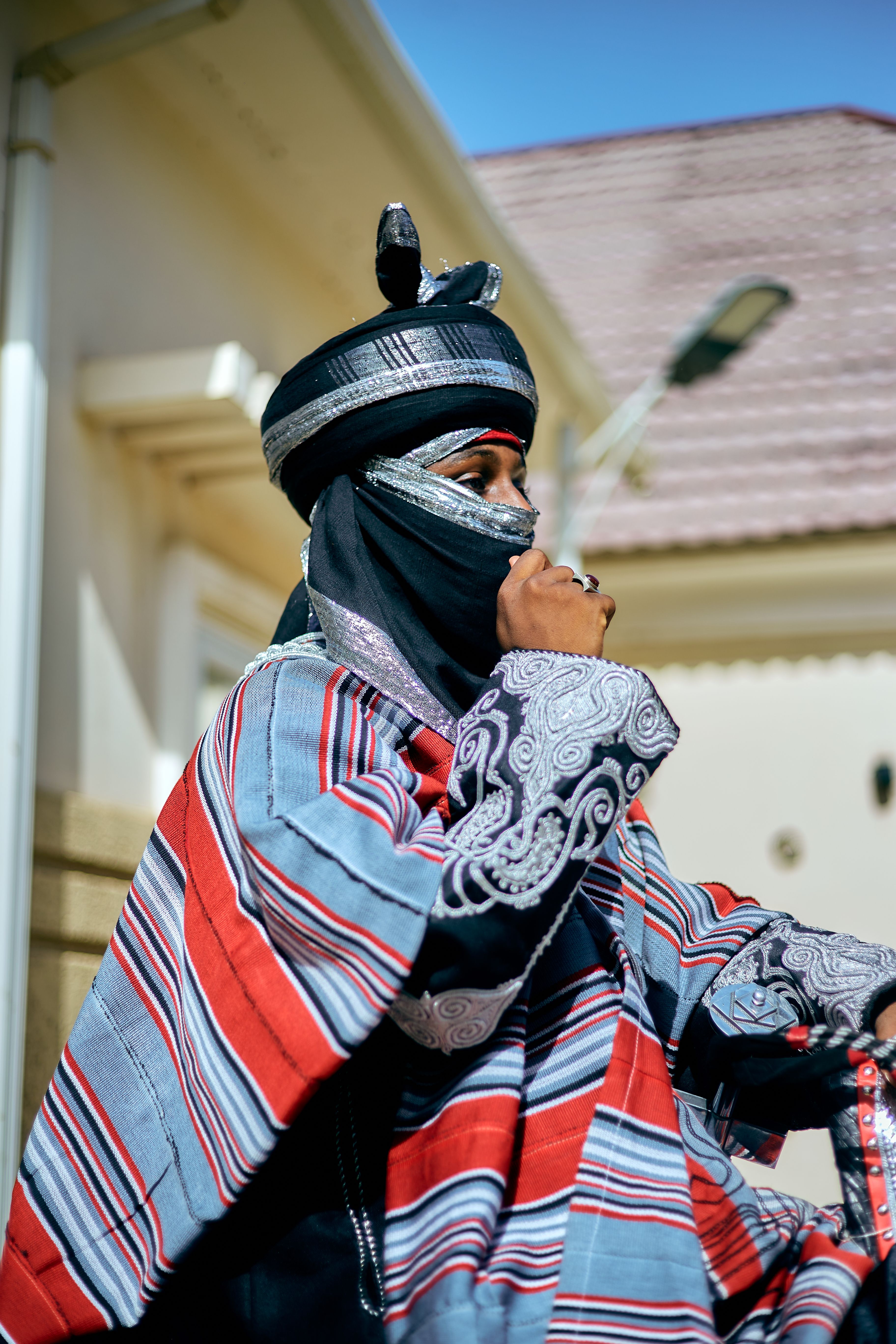 A person in intricate traditional attire outdoors, capturing cultural essence.