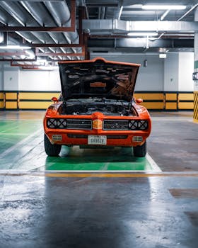 Classic vintage muscle car with open hood in an indoor parking garage, offering a retro vibe.
