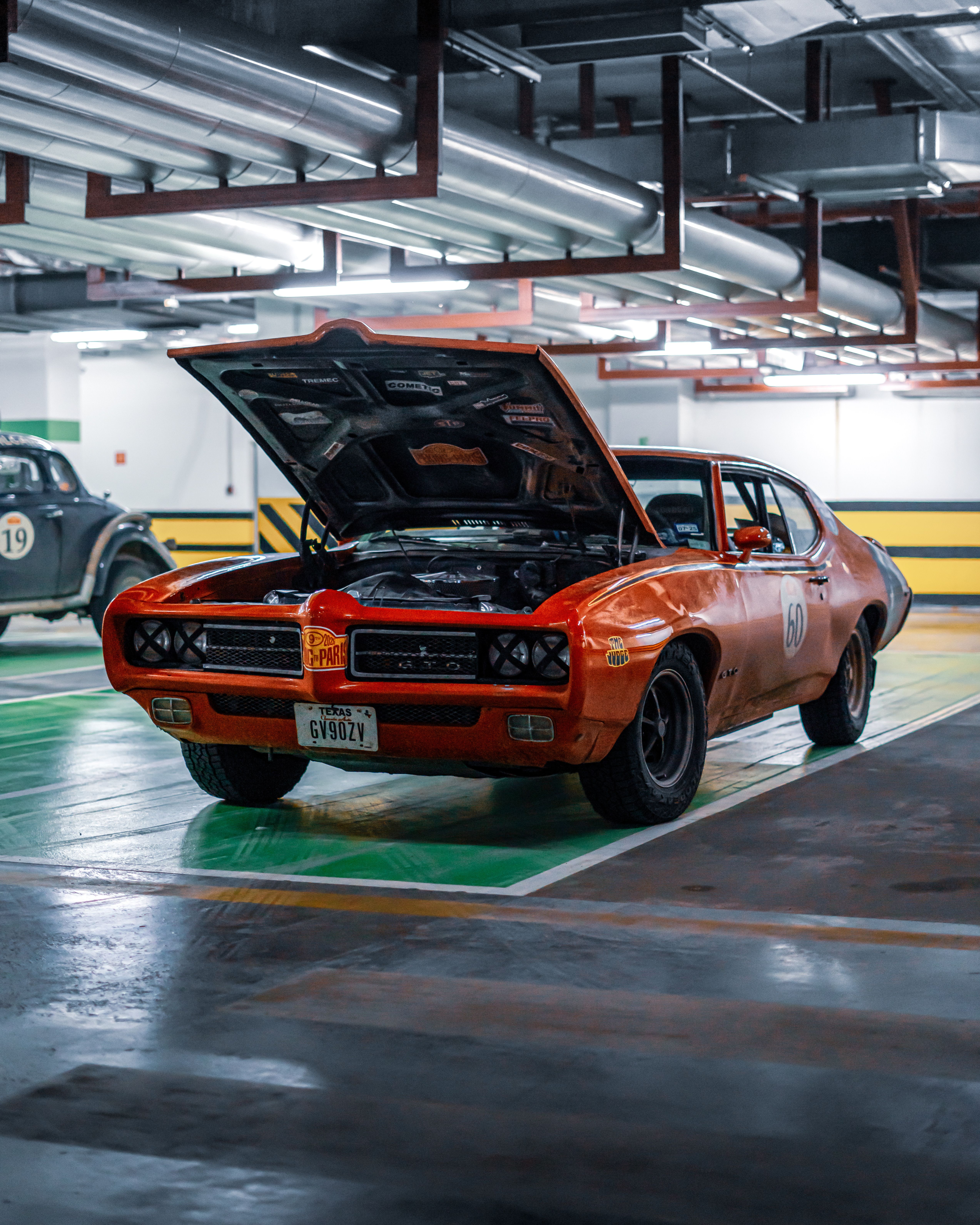 Vintage muscle car with open hood in a modern parking garage, Ankara, Türkiye.