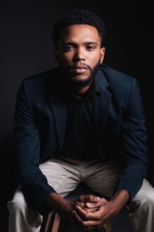 Free Elegant portrait of a young man in a suit with a dramatic dark background. Stock Photo