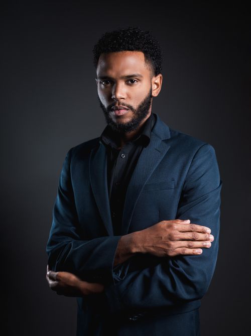 Free Portrait of a confident businessman in a dark suit on a black background. Stock Photo