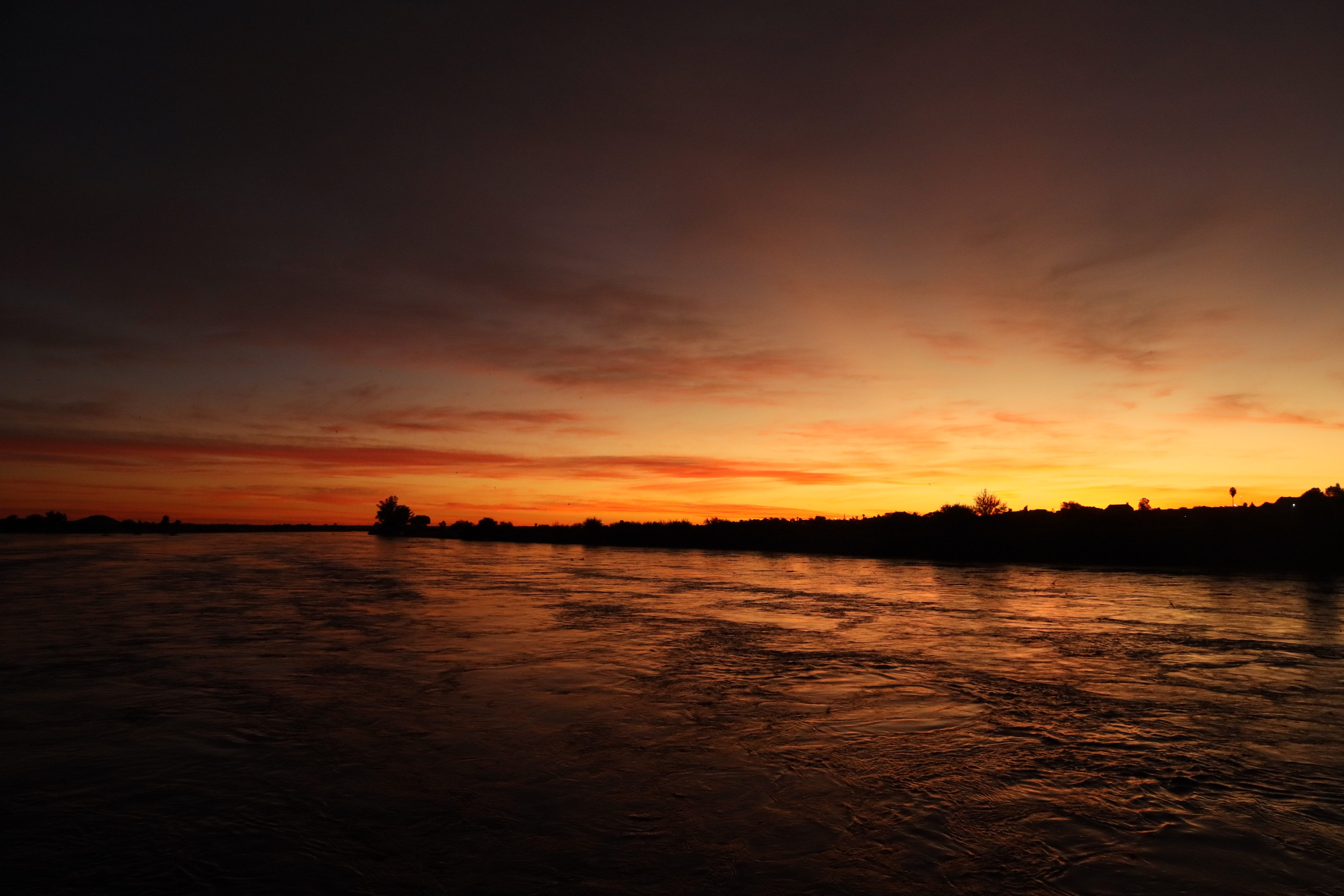 Breathtaking view of a vibrant sunset over a calm river, creating a warm and serene mood.