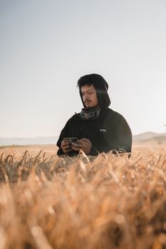 Drone operator in a wheat field wearing virtual reality gear, focused and intent.