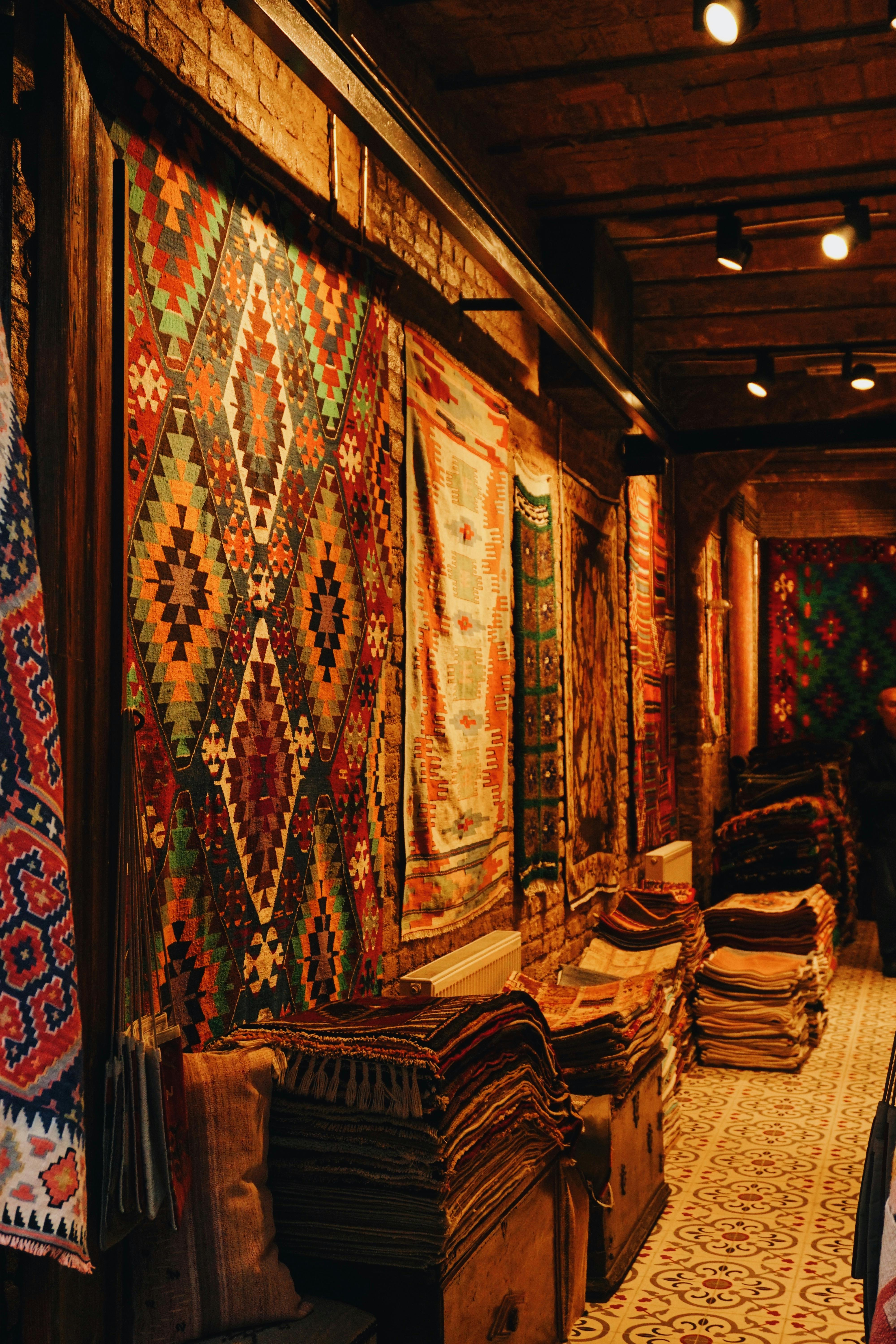 Vibrant traditional rugs hanging in a cozy indoor bazaar setting.