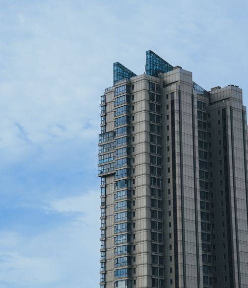 Free Tall modern skyscraper against a blue sky with geometric architectural design. Stock Photo