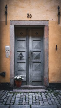 Weathered blue door with flower pot in an old cobblestone alley, 3C sign above.