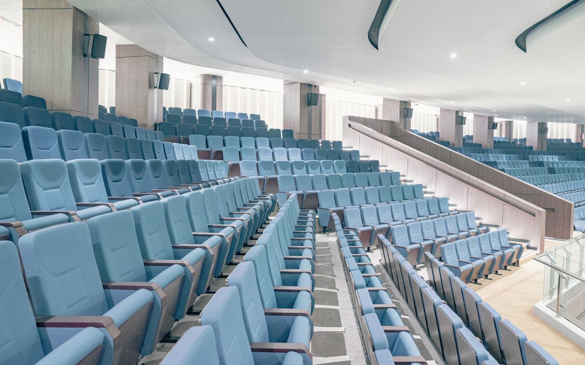 Spacious modern auditorium featuring blue seats and minimalist architecture, ideal for events or presentations.