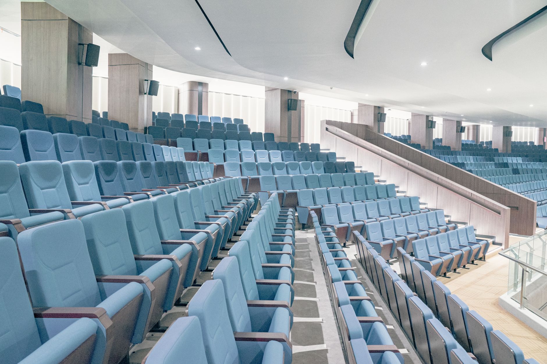 Spacious modern auditorium featuring blue seats and minimalist architecture, ideal for events or presentations.