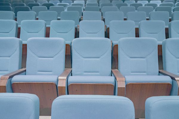 Rows of empty blue seats in a modern auditorium. Photo by Miff Ibra on Pexels.