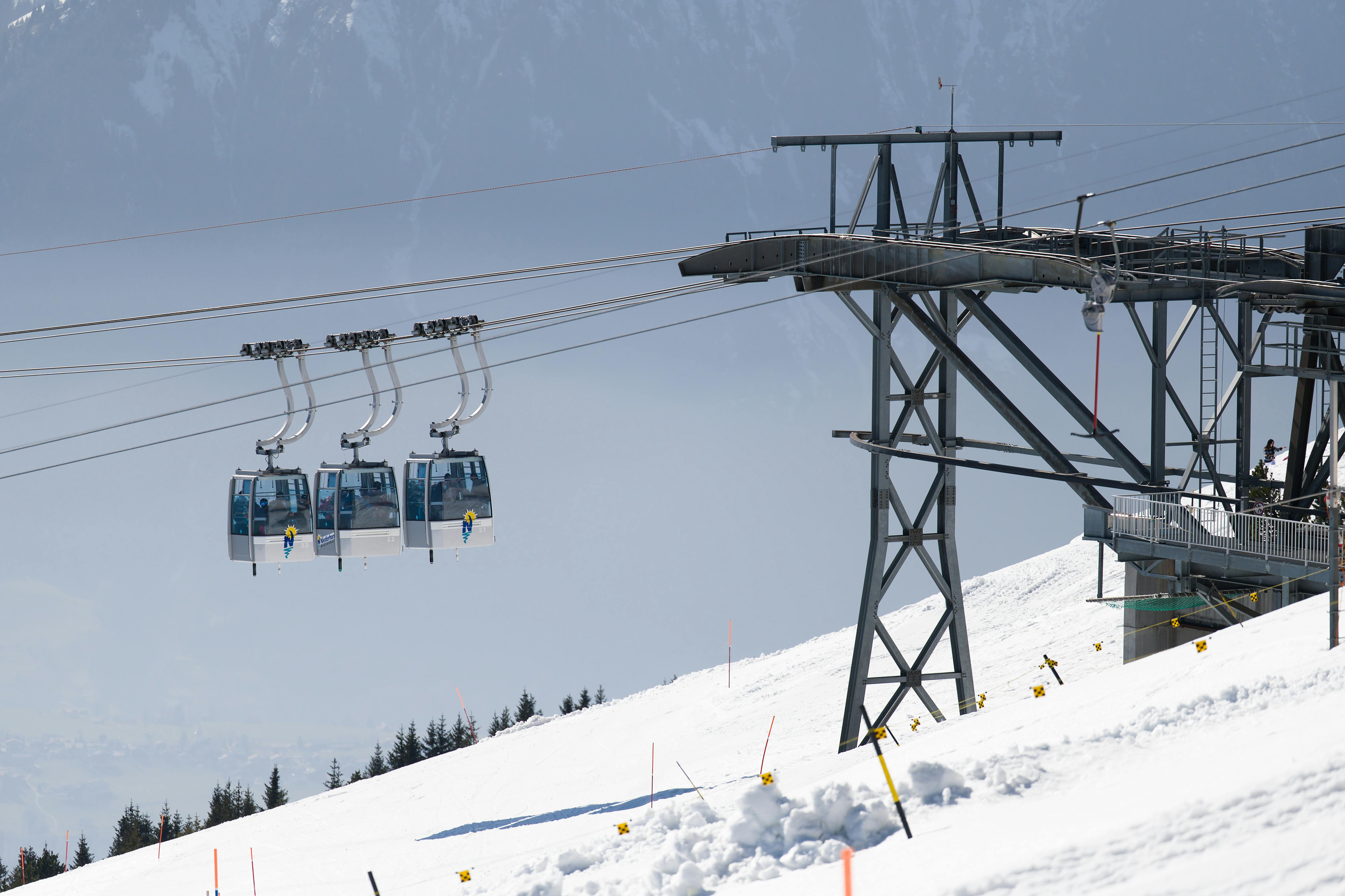 Scenic view of cable cars ascending snowy Alps, ideal for winter adventures.