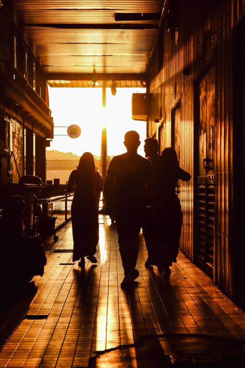 Free Silhouetted people walking through a sunlit corridor creating a dramatic shadow effect. Stock Photo