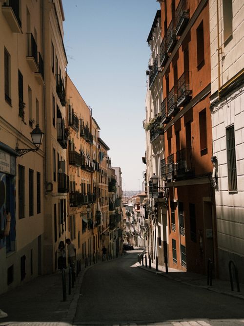 Free A picturesque narrow street lined with colorful buildings in a sunlit European city, evoking a vintage charm. Stock Photo