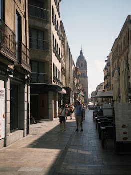 Explore a historic street scene with European architecture, lively pedestrians, and a prominent bell tower.
