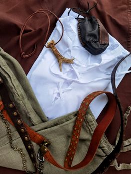 Medieval styled accessories and garments laid out in a flat lay composition, featuring leather and textiles.