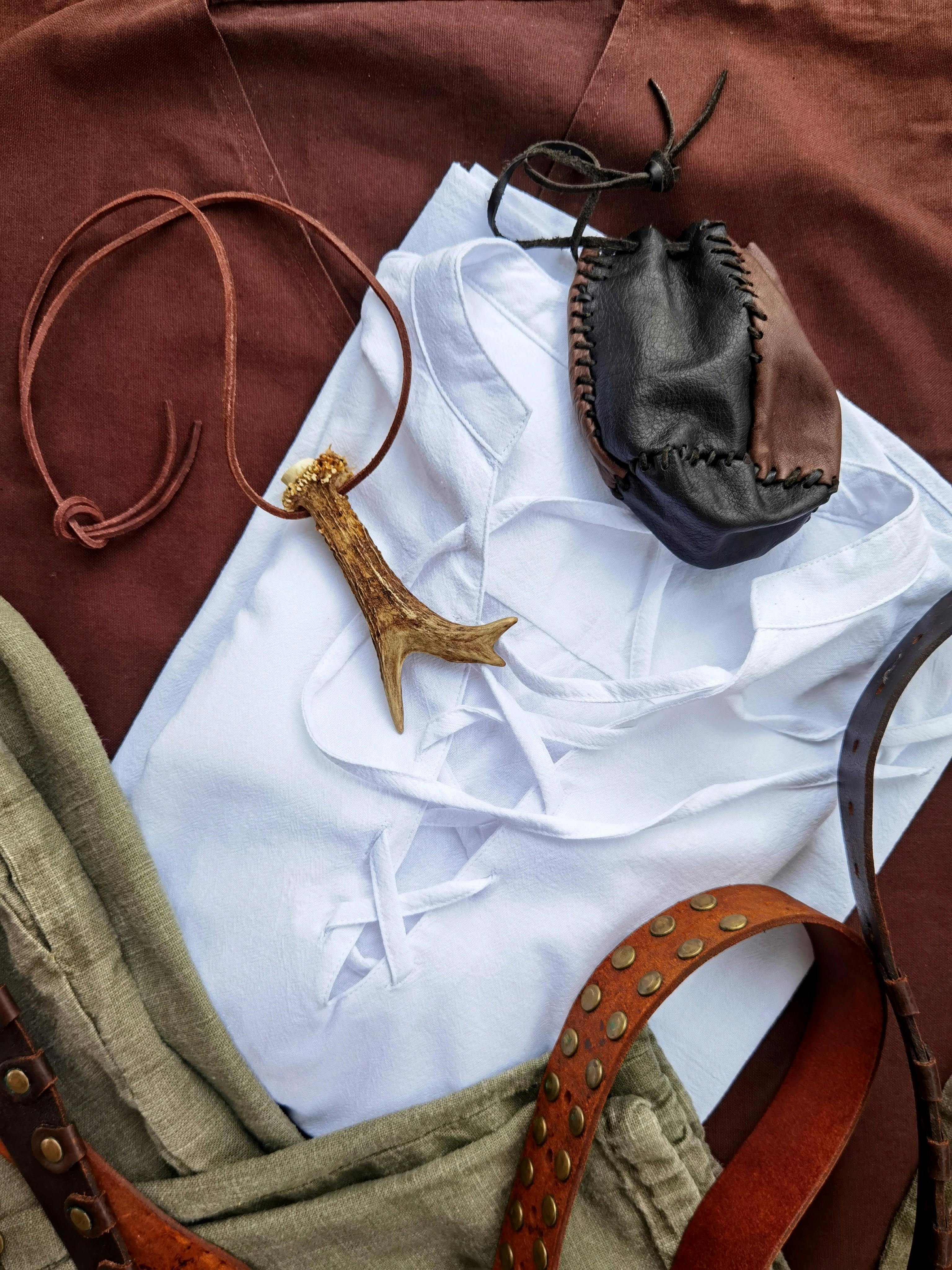 Gratuit Mise à plat d'une tenue viking médiévale comprenant une pochette en cuir, un collier en corne et des tissus en lin. Photos