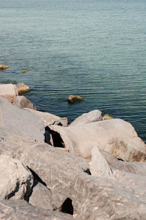 Free Serene view of a rocky shoreline with calm ocean waters under a clear sky. Stock Photo