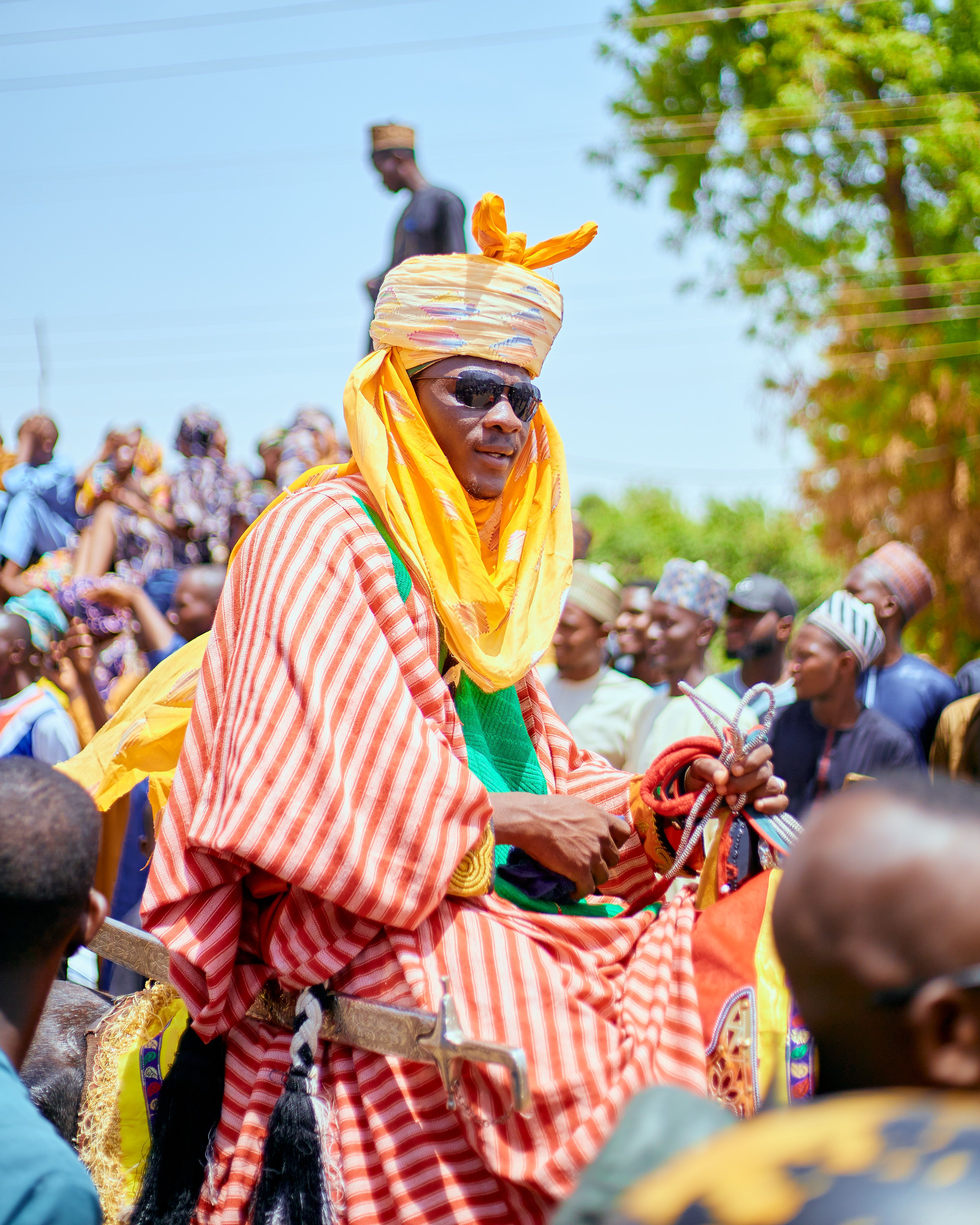 A vibrant outdoor parade showcasing traditional attire with a person on horseback.