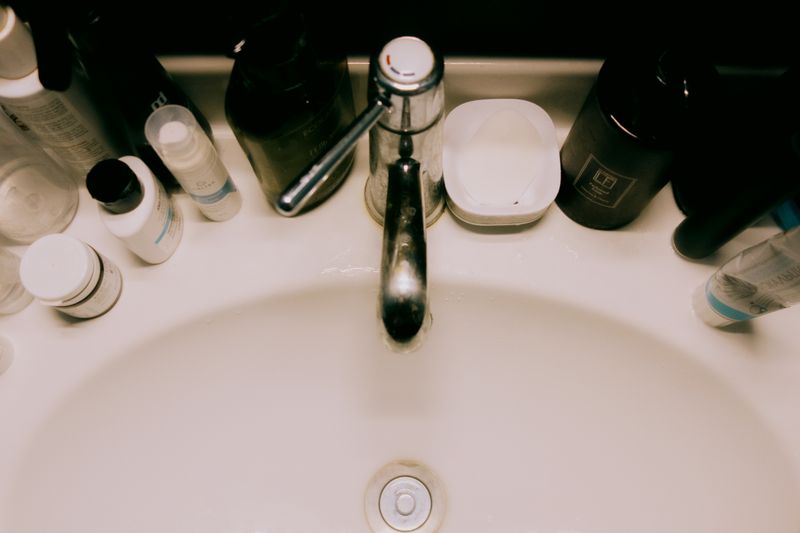 Overhead view of a bathroom sink surrounded by various toiletries, offering a modern minimalist aesthetic.