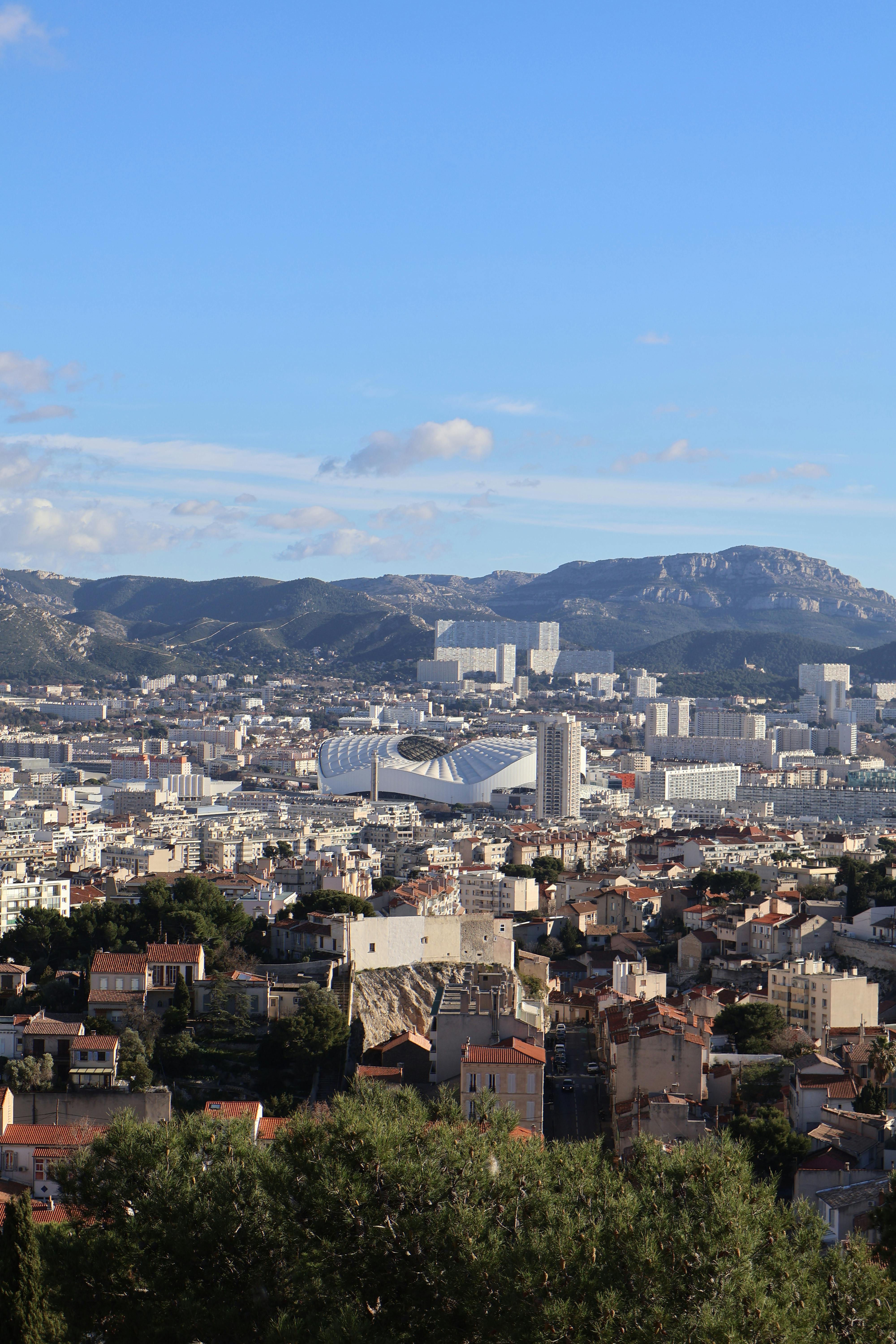 Explore a panoramic view of Marseille, France, with distant mountains under a bright summer sky.