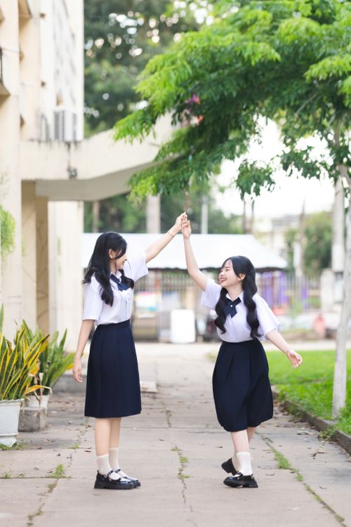 Free Two students in school uniforms enjoying a playful moment outdoors, celebrating friendship. Stock Photo