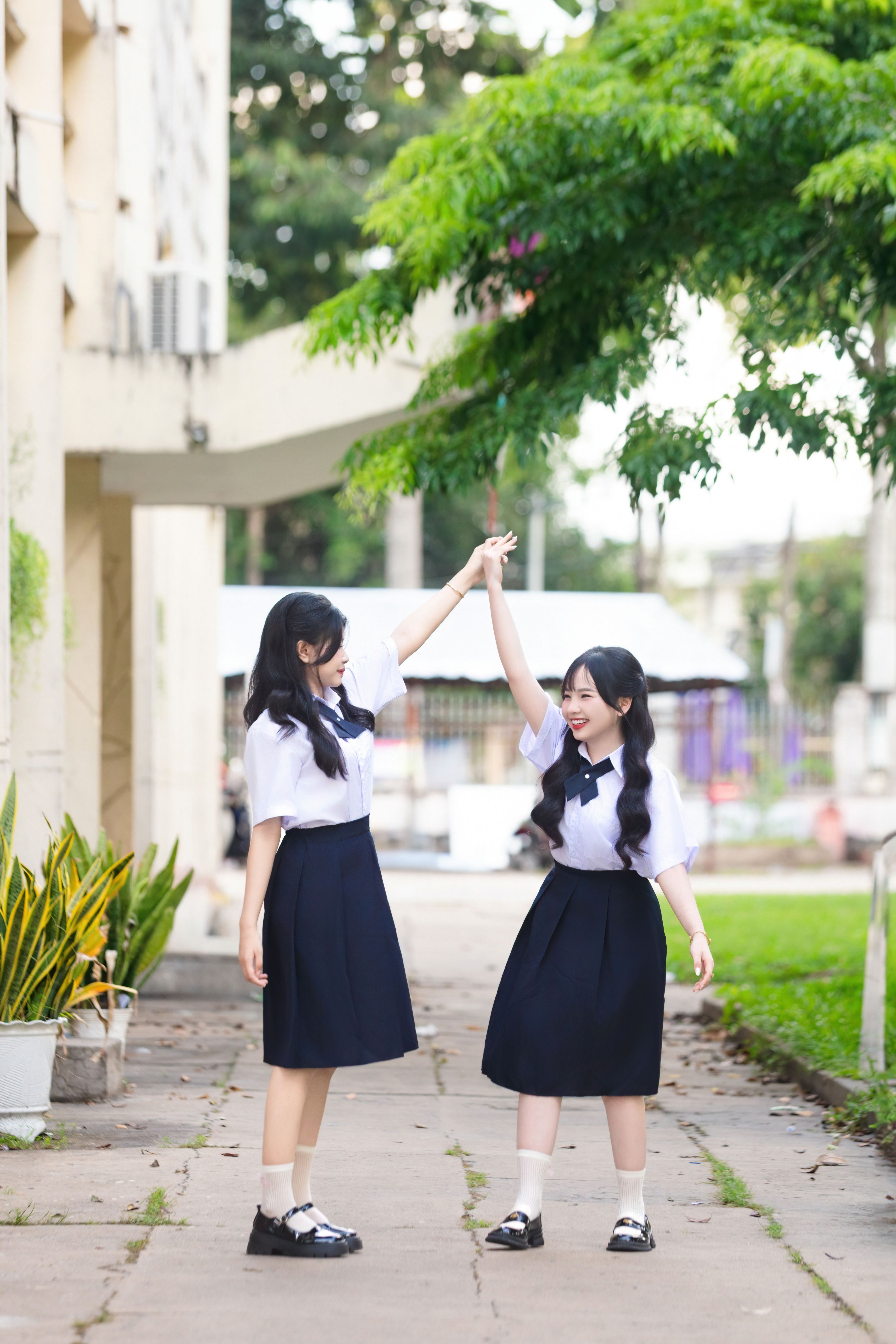 Two Girls in School Uniforms Holding Hands Outdoors · Free Stock Photo