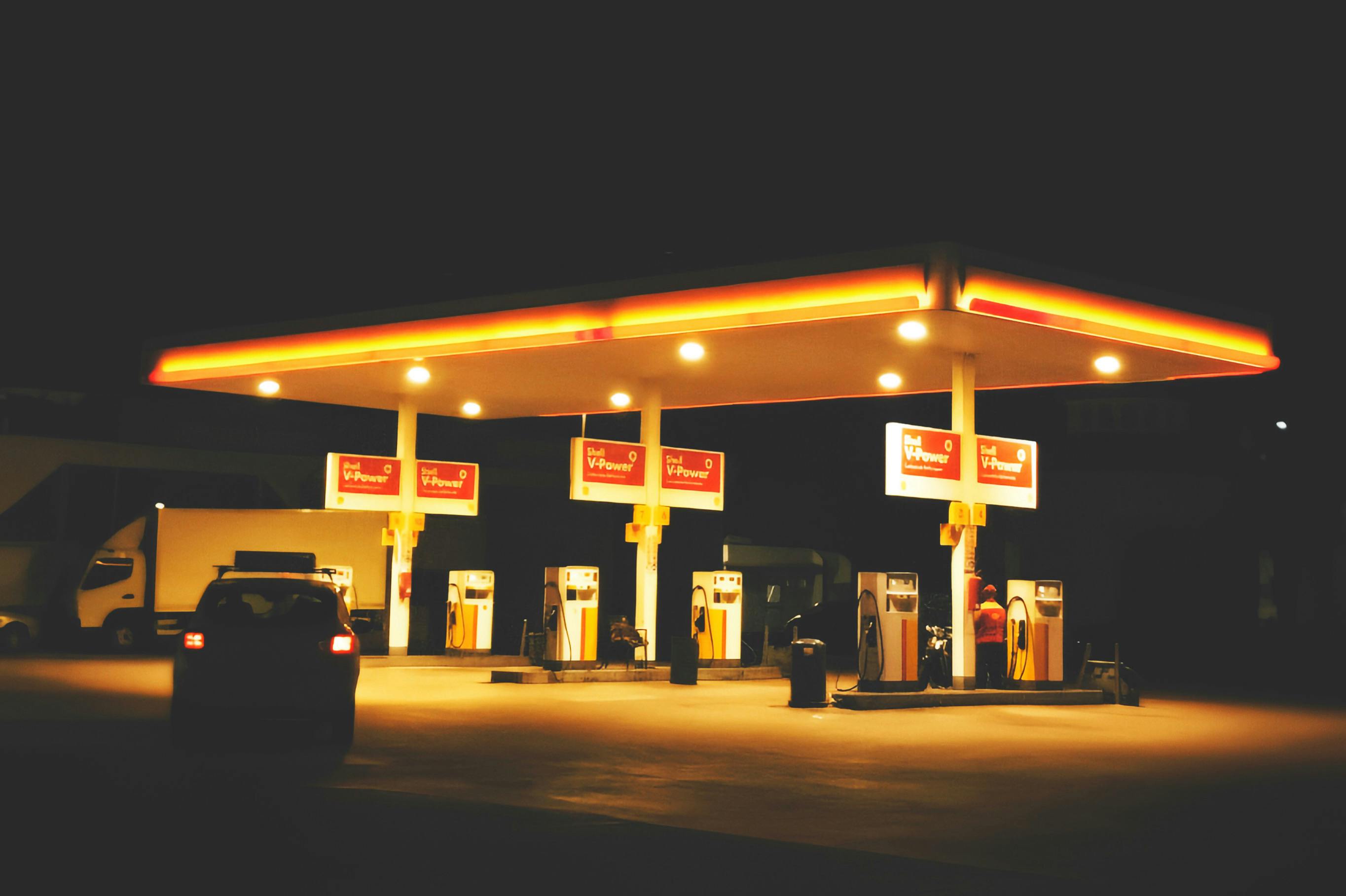 A gas station lit up at night, showcasing signage and fueling pumps under bright lights.