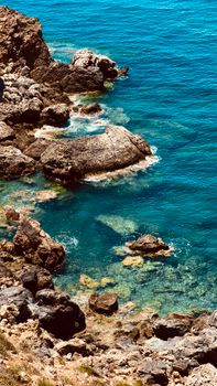A beautiful rocky coastline with vibrant turquoise waters under a clear summer sky in Cyprus.