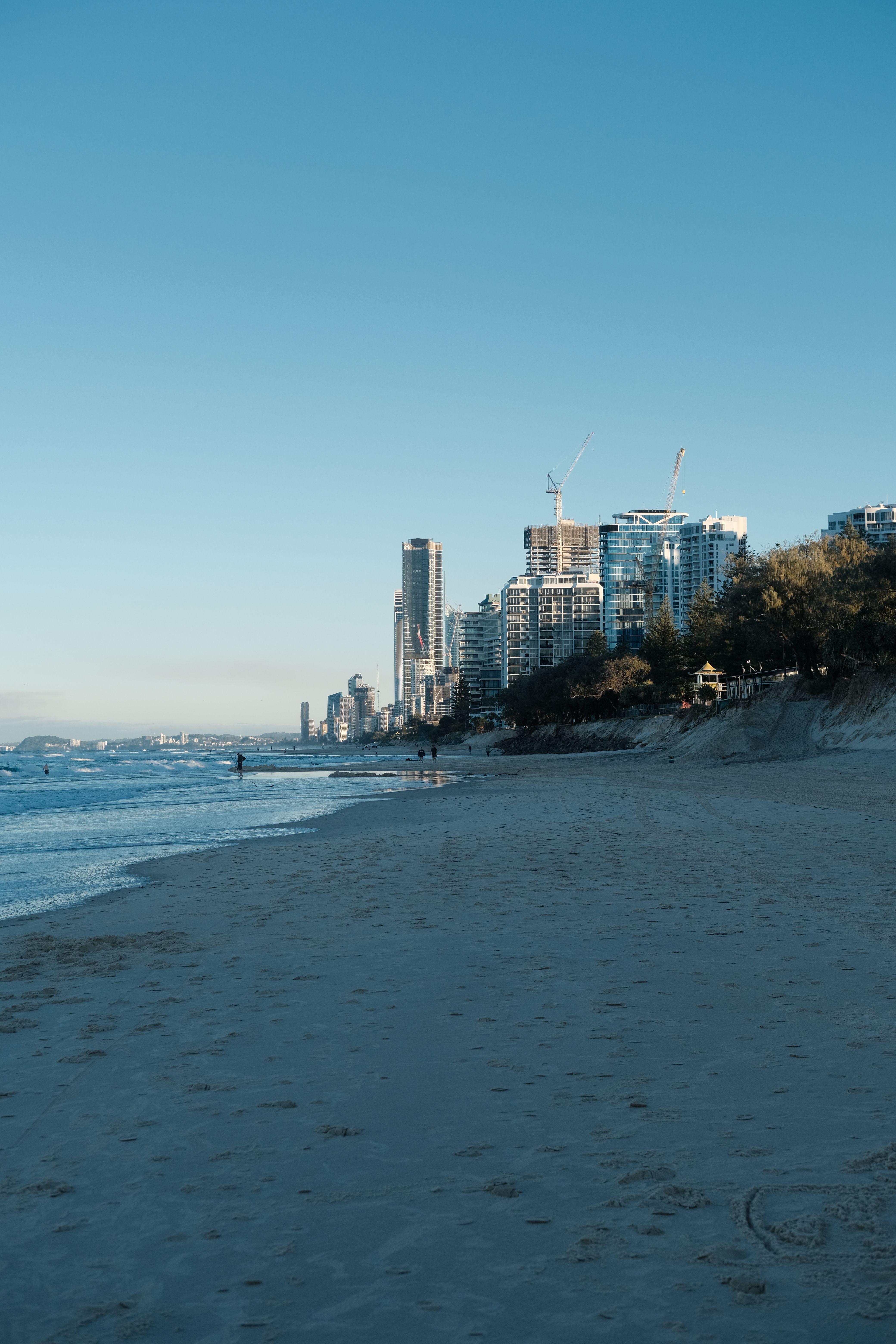 Tranquil shoreline with modern cityscape under the morning sky, capturing a peaceful coastal urban scene.